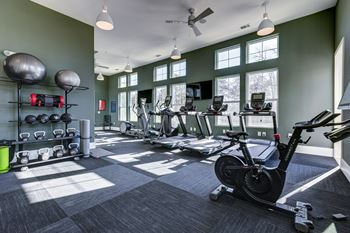 a gym with weights and cardio equipment and windows